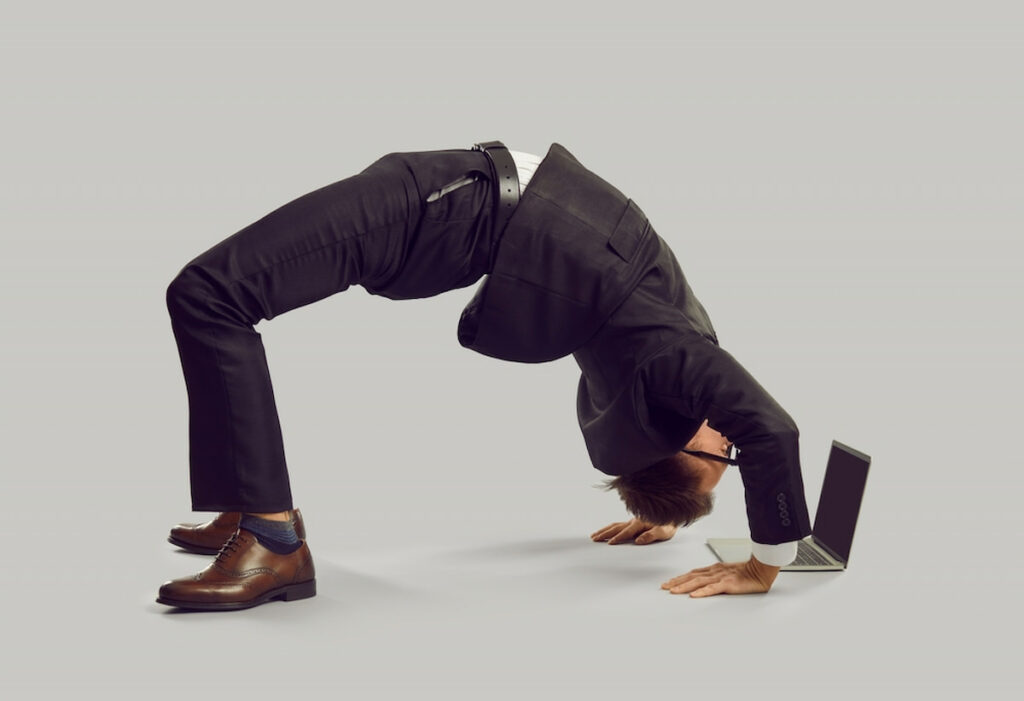 A funny photo of a man doing a backbend while he works with flexible database management.