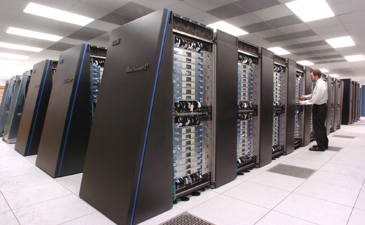 A man stands in a database farm. He has been monitoring and managing the servers with software.