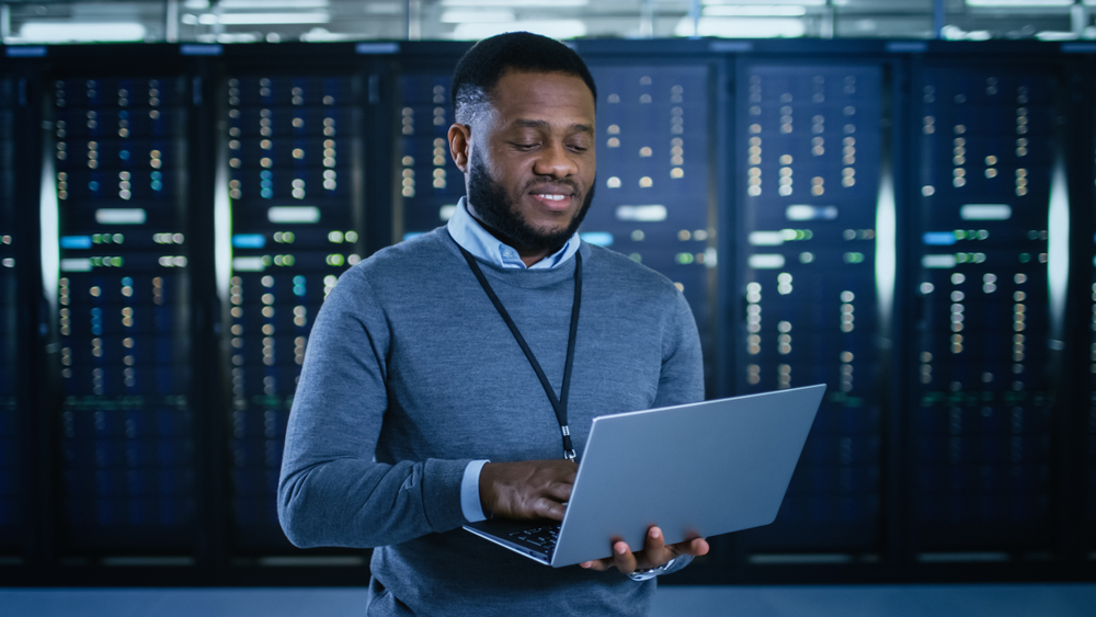 Man works to prevent database disasters while standing in front of a server